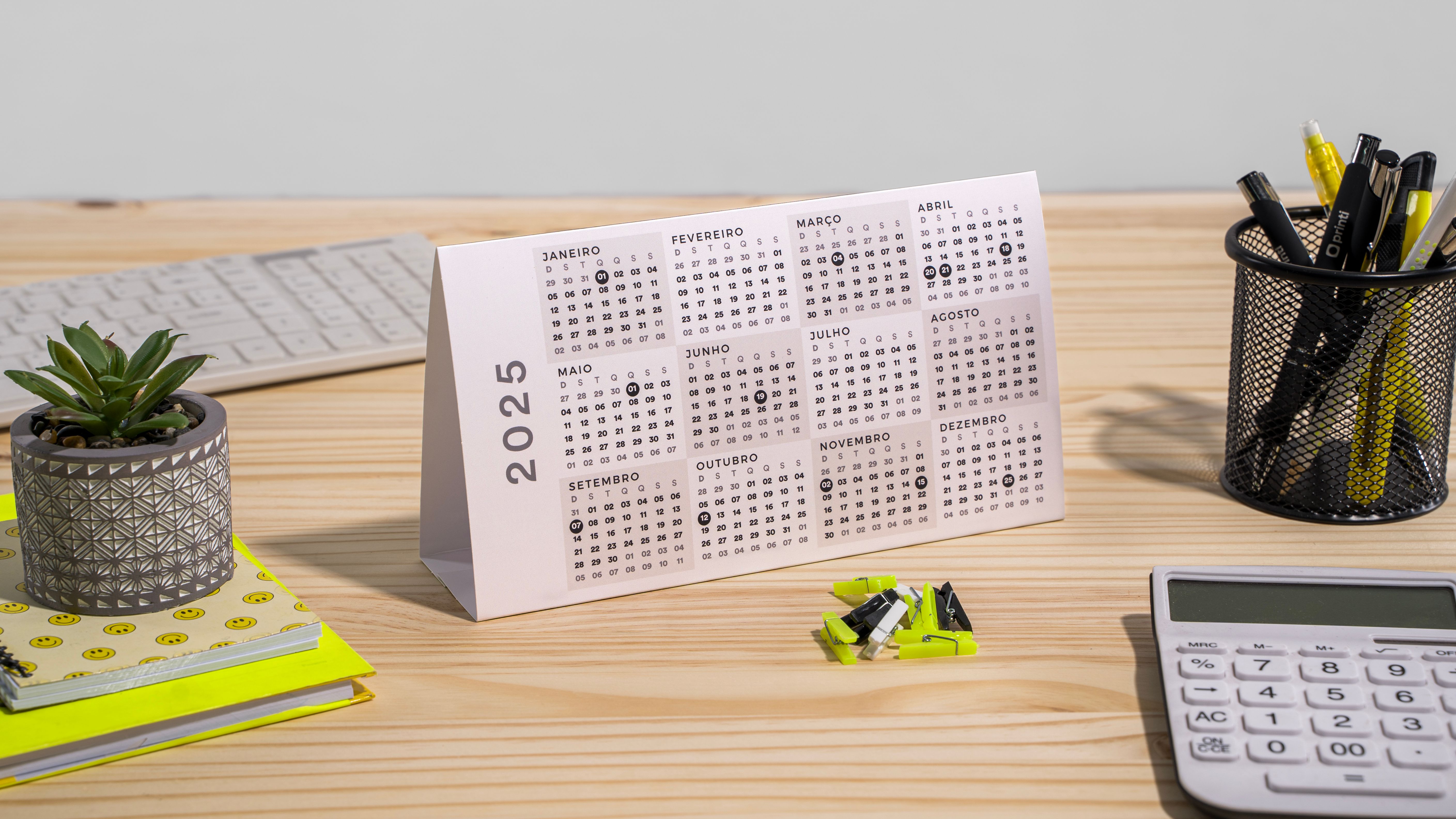 calendario de mesa de 2025 em cima de uma mesa de madeira rodeada de itens de decoração