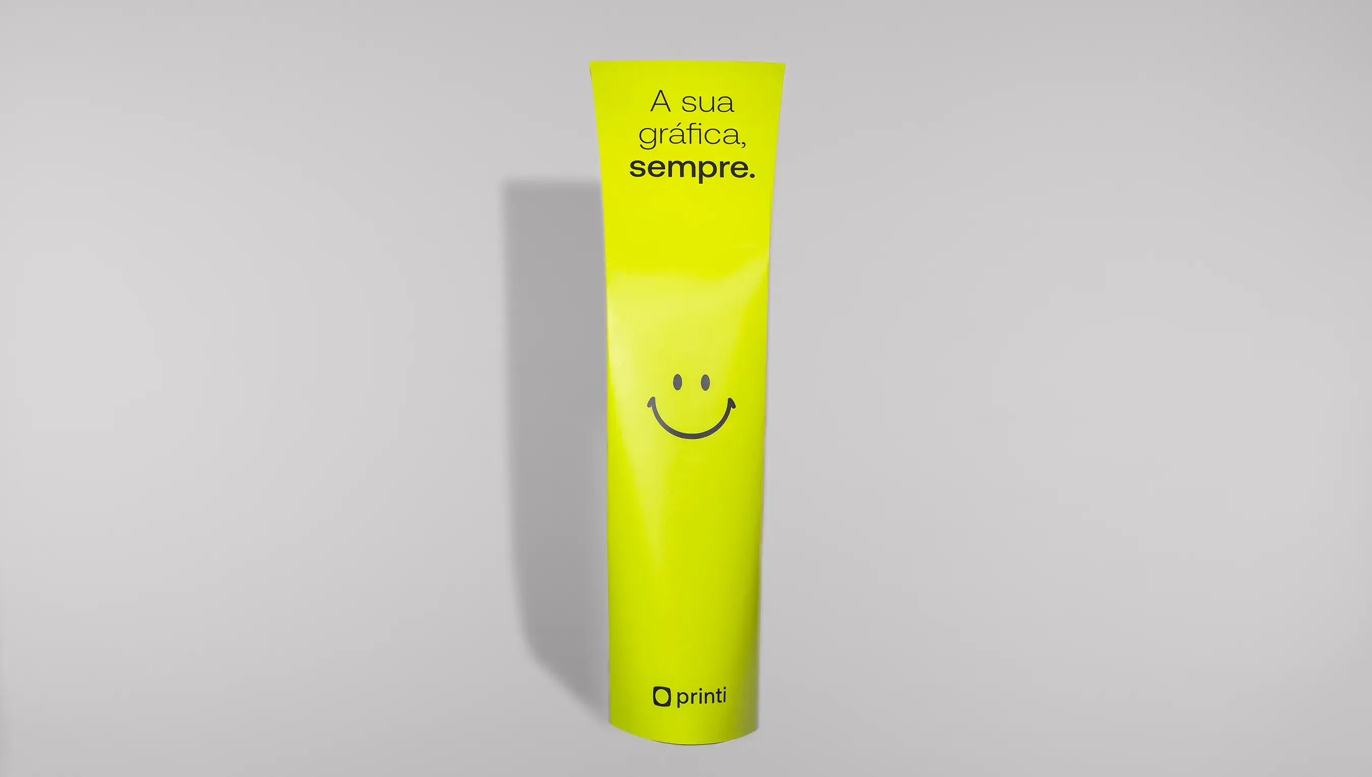 Totem banana da Printi em verde, na vertical, com um smile, nome e logo da Printi e frase personalizada
