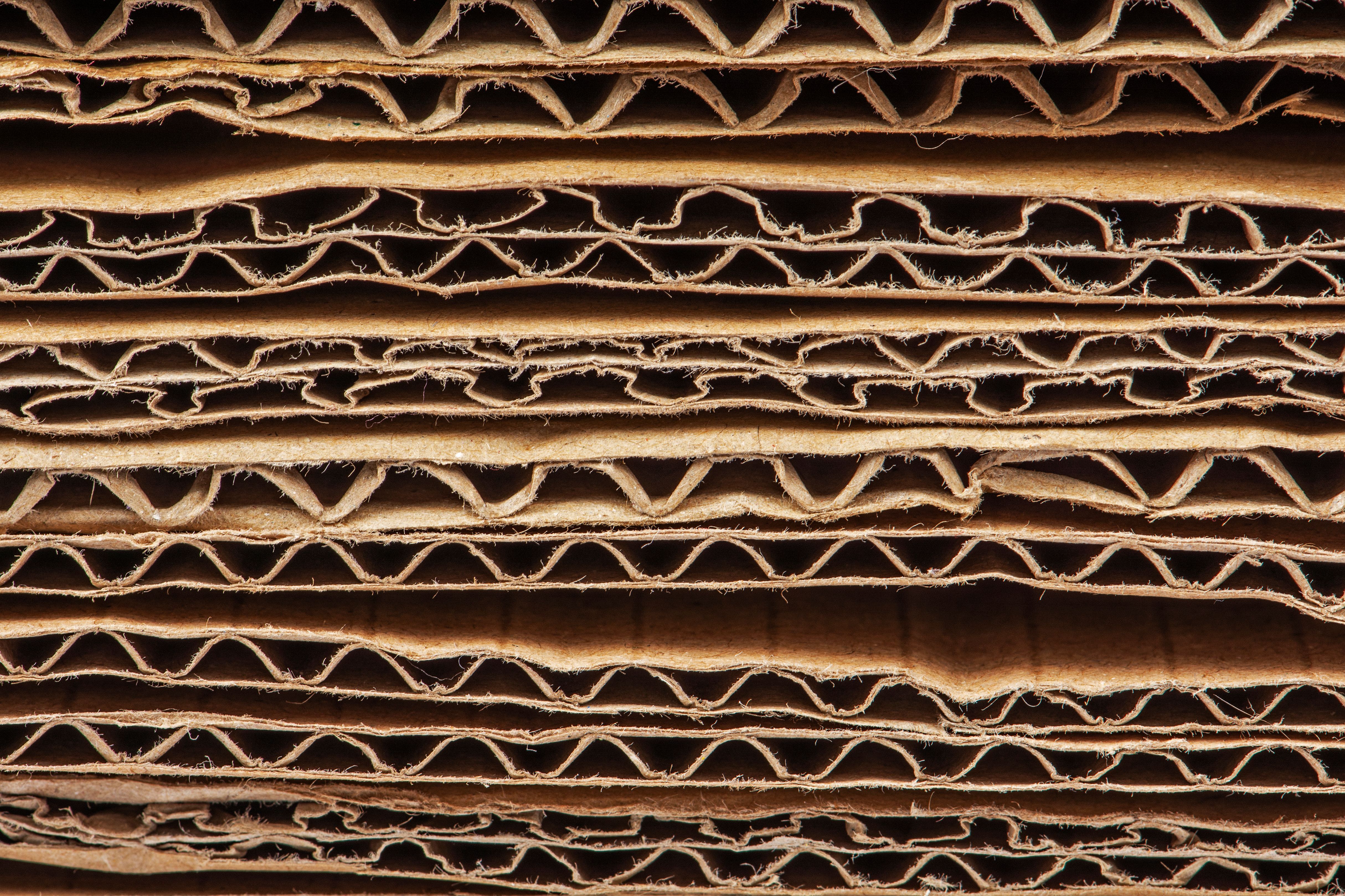 Close em um pilha de papelão ondulado em camadas, mostrando a estrutura interna com ondulações