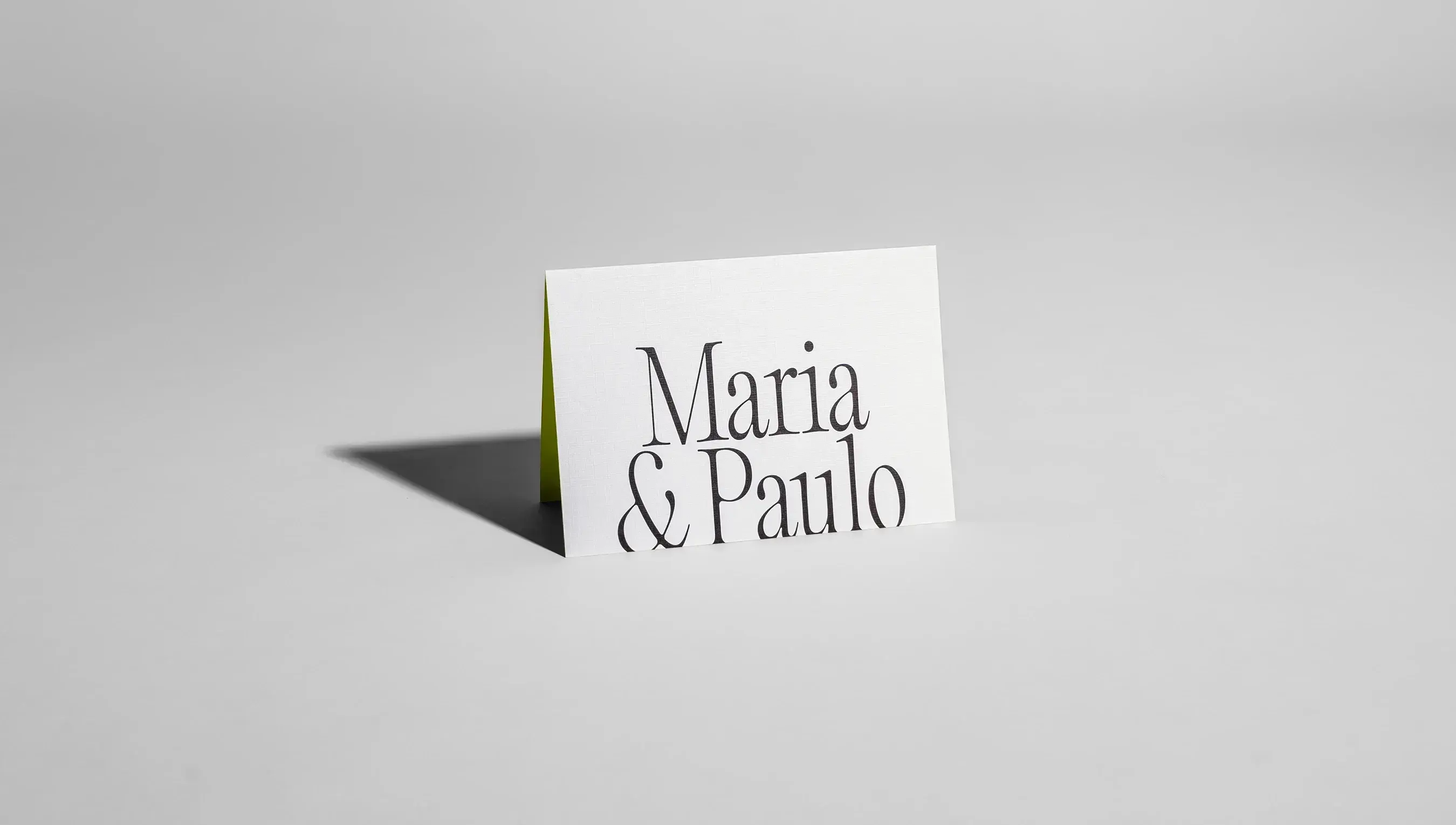 convite de casamento branco com os nomes maria e paulo. O convite está exposto em uma plataforma branca e lisa