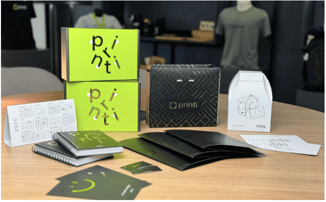 Foto de produtos de papelaria e brindes personalizados da marca Printi, com embalagens criativas, cadernos, calendários, folders, caixas com hot stamping e design moderno. Os materiais combinam acabamentos em verniz e hot stamping para destacar a identida